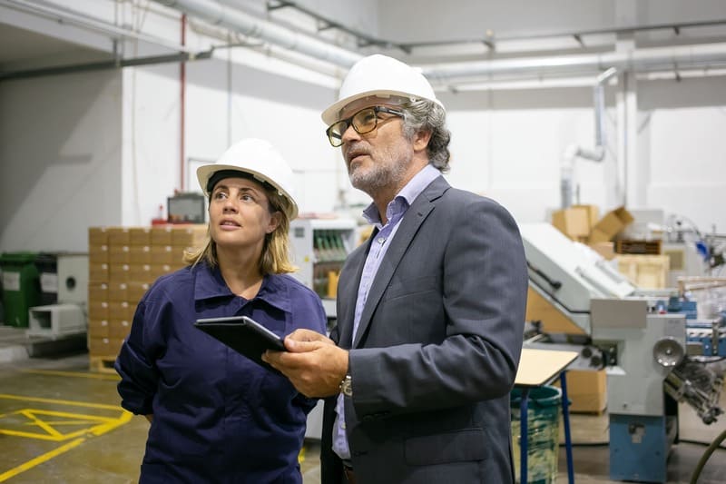 confident-bearded-supervisor-talking-with-female-plant-worker-holding-tablet (1)